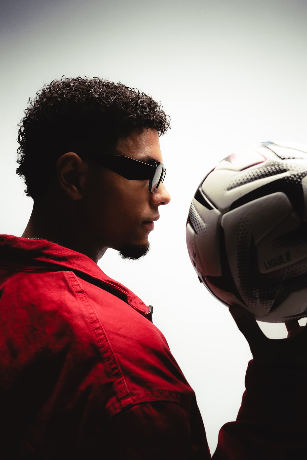 ELIKIA in a red jacket holding a football